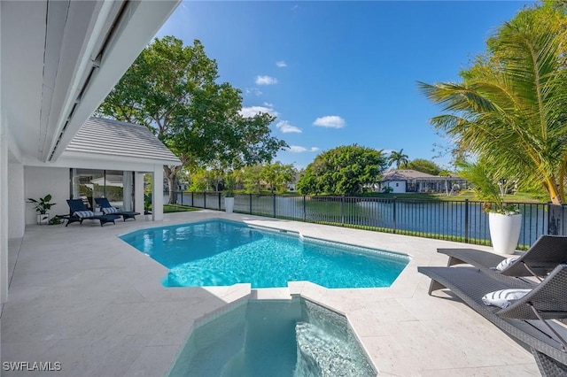 view of pool featuring a pool with connected hot tub, a patio area, a water view, and a fenced backyard