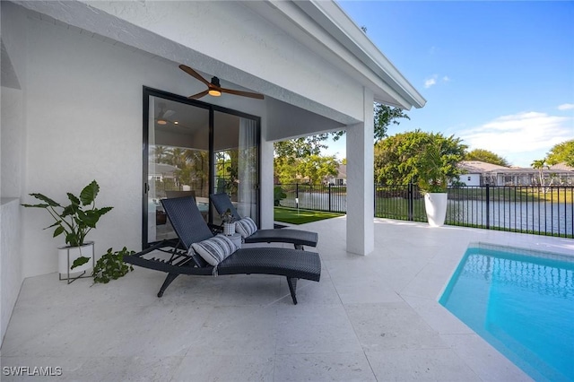 view of pool with a water view, fence, a ceiling fan, a fenced in pool, and a patio area