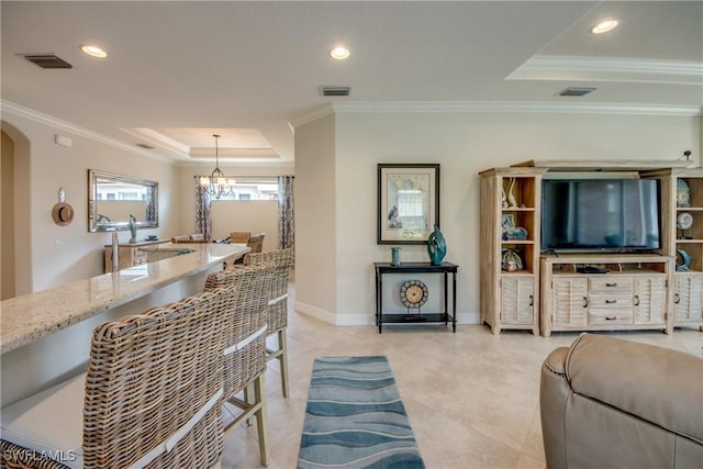 living area with ornamental molding, a tray ceiling, and visible vents