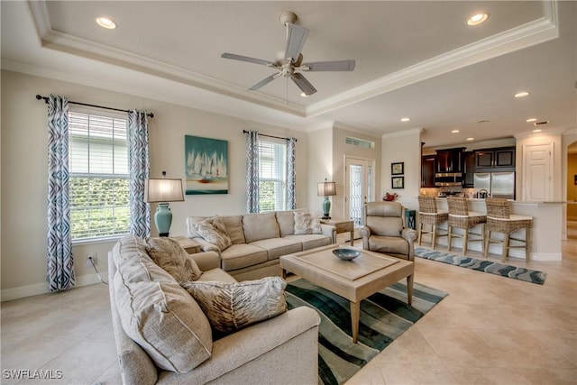 living room with baseboards, light tile patterned flooring, a raised ceiling, and crown molding