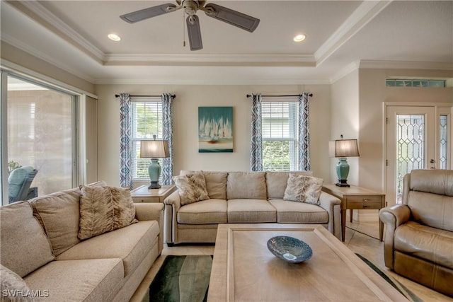 living area with ornamental molding, a raised ceiling, and a healthy amount of sunlight