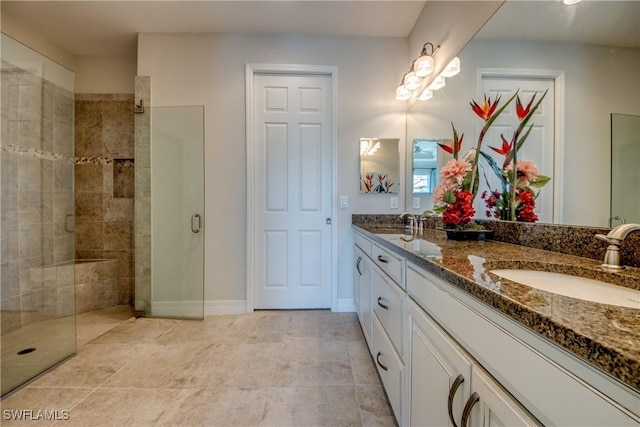 bathroom featuring double vanity, baseboards, a sink, and tiled shower