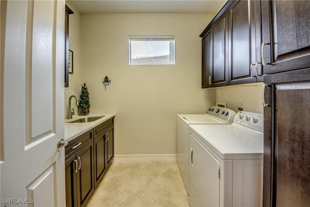 clothes washing area featuring cabinet space, baseboards, separate washer and dryer, and a sink