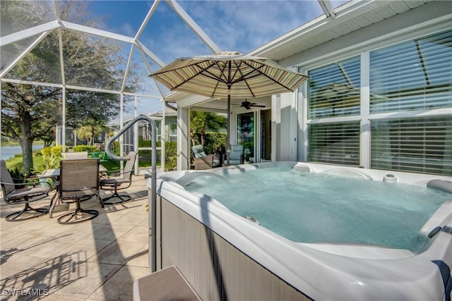 view of patio featuring a ceiling fan, glass enclosure, a hot tub, and area for grilling