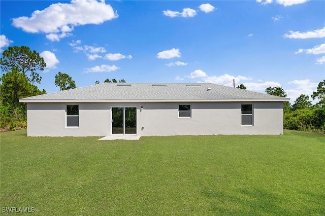 back of house featuring roof with shingles, a lawn, and stucco siding