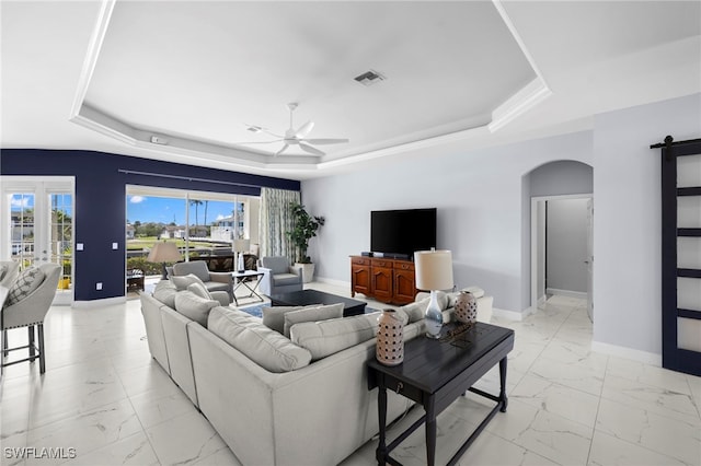 living area with marble finish floor, a tray ceiling, and arched walkways