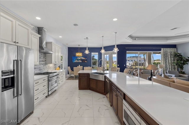 kitchen with wall chimney range hood, high quality appliances, marble finish floor, and a sink