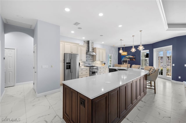 kitchen featuring marble finish floor, wall chimney exhaust hood, visible vents, and high end appliances