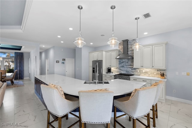 kitchen with marble finish floor, wall chimney exhaust hood, visible vents, and appliances with stainless steel finishes