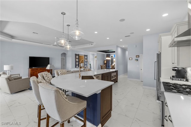 kitchen featuring arched walkways, open floor plan, marble finish floor, high end stainless steel range oven, and light countertops