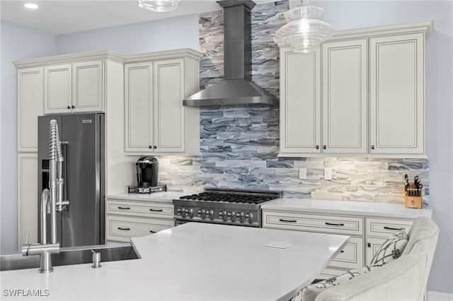 kitchen with wall chimney exhaust hood, light countertops, stainless steel fridge, and range