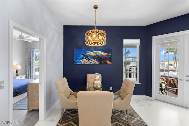 dining area with an accent wall, marble finish floor, a notable chandelier, and baseboards