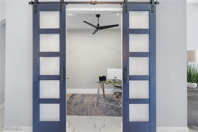 interior space with marble finish floor, a barn door, baseboards, and a ceiling fan