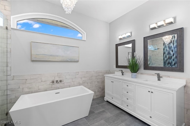 bathroom with double vanity, tiled shower, a freestanding tub, and a sink