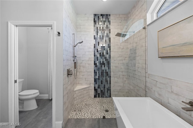 bathroom featuring toilet, a garden tub, baseboards, and a tile shower