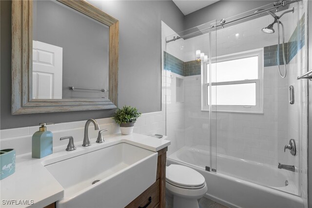 bathroom with enclosed tub / shower combo, vanity, and toilet