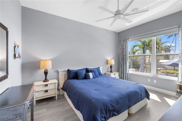 bedroom with ceiling fan, wood finished floors, and baseboards