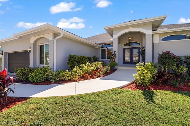 view of exterior entry with a garage, french doors, and stucco siding