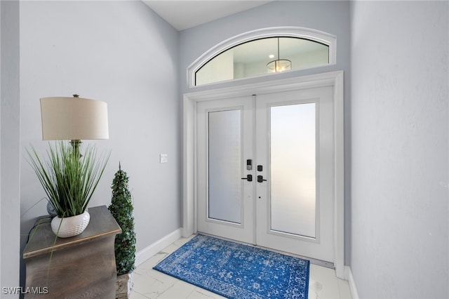 foyer featuring marble finish floor, baseboards, and french doors