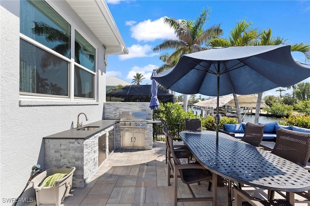 view of patio with outdoor dining area, grilling area, a sink, and area for grilling