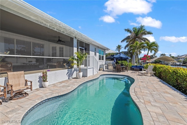 outdoor pool featuring a sunroom, a patio, and ceiling fan