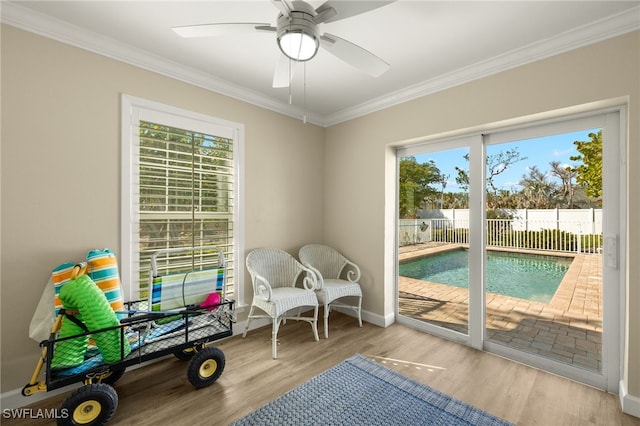 interior space featuring a ceiling fan, crown molding, baseboards, and wood finished floors