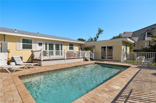 back of house featuring a fenced in pool, a patio area, metal roof, fence, and a wooden deck