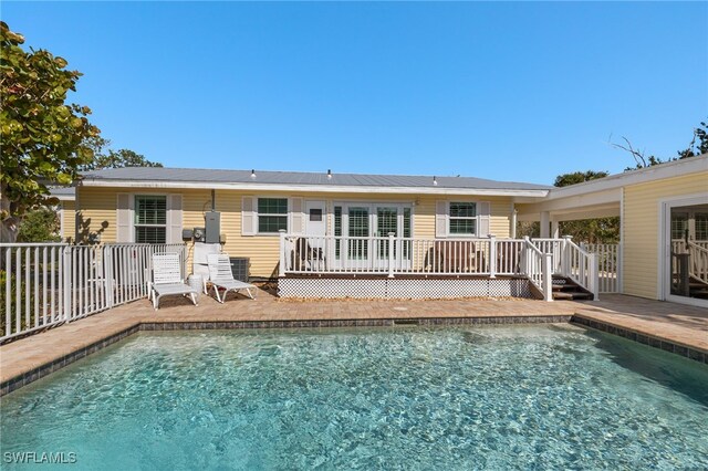 rear view of property featuring an outdoor pool, fence, and a deck