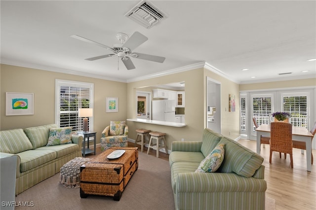 living room featuring light wood-style floors, visible vents, crown molding, and baseboards