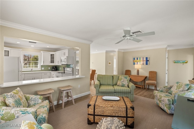 living area with visible vents, wood finished floors, and ornamental molding