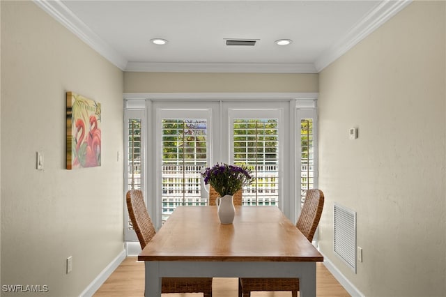 dining room with baseboards, ornamental molding, visible vents, and light wood-style floors