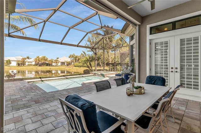 view of patio / terrace featuring french doors, a pool with connected hot tub, a water view, a ceiling fan, and a lanai