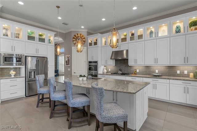 kitchen with crown molding, a center island with sink, stainless steel appliances, backsplash, and under cabinet range hood