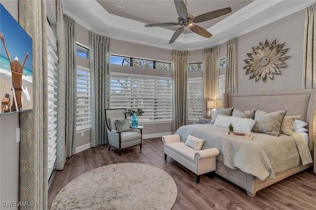 bedroom featuring crown molding, baseboards, a raised ceiling, and wood finished floors