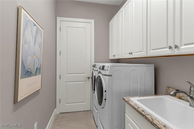 clothes washing area with separate washer and dryer, a sink, cabinet space, and baseboards