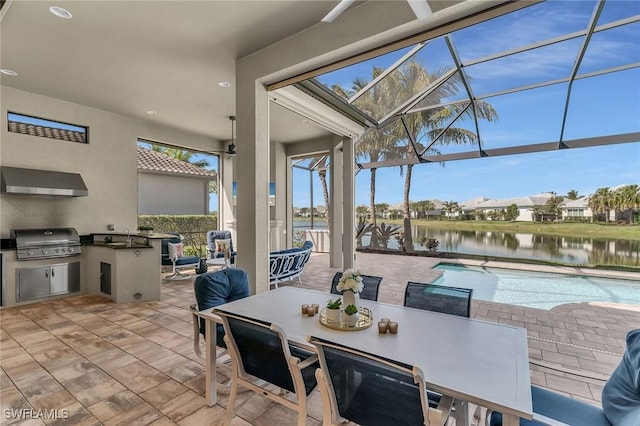 view of patio / terrace featuring a water view, area for grilling, exterior kitchen, a lanai, and an outdoor pool