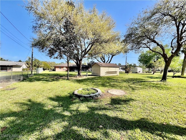 view of yard with fence, an outdoor structure, and a storage shed