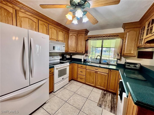 kitchen featuring light tile patterned floors, white appliances, brown cabinetry, and a sink