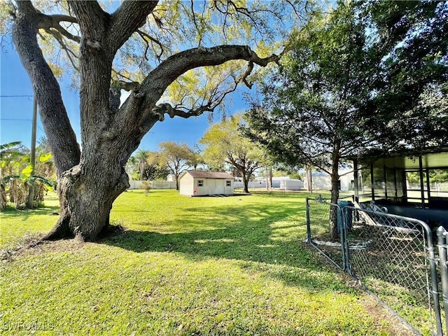 view of yard featuring a storage shed, fence, and an outbuilding