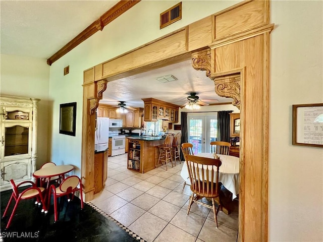 kitchen with french doors, light tile patterned floors, dark countertops, visible vents, and white appliances