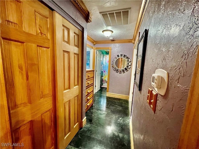 corridor with crown molding, visible vents, a textured wall, a textured ceiling, and baseboards