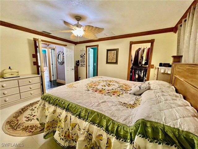 bedroom with ceiling fan, visible vents, a closet, a walk in closet, and crown molding