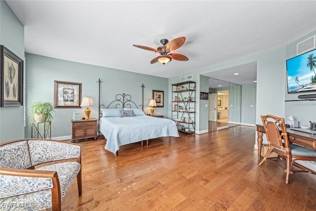 bedroom with ceiling fan, visible vents, baseboards, and wood finished floors