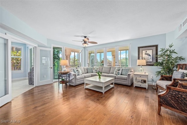 living area featuring hardwood / wood-style floors, a healthy amount of sunlight, baseboards, and a textured ceiling