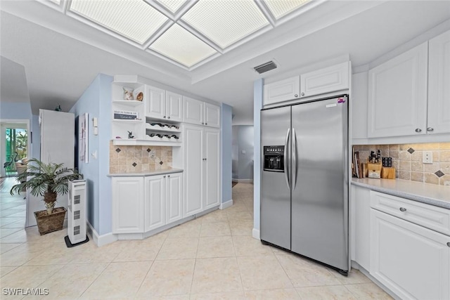 kitchen with visible vents, stainless steel refrigerator with ice dispenser, open shelves, light countertops, and light tile patterned floors