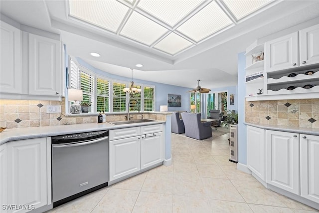 kitchen with light countertops, stainless steel dishwasher, light tile patterned flooring, white cabinets, and a sink