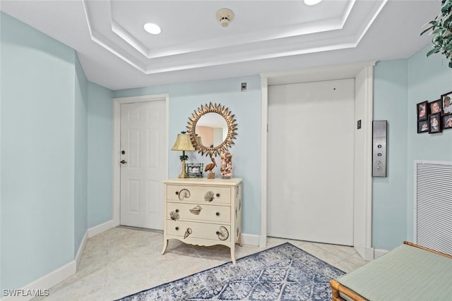 interior space with a tray ceiling, baseboards, visible vents, and light tile patterned flooring