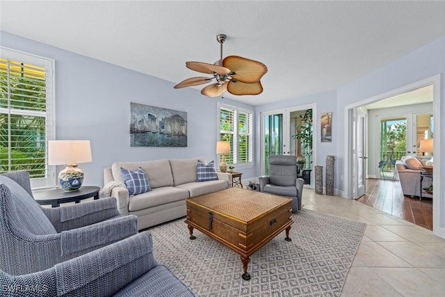 tiled living room featuring a healthy amount of sunlight, baseboards, and a ceiling fan