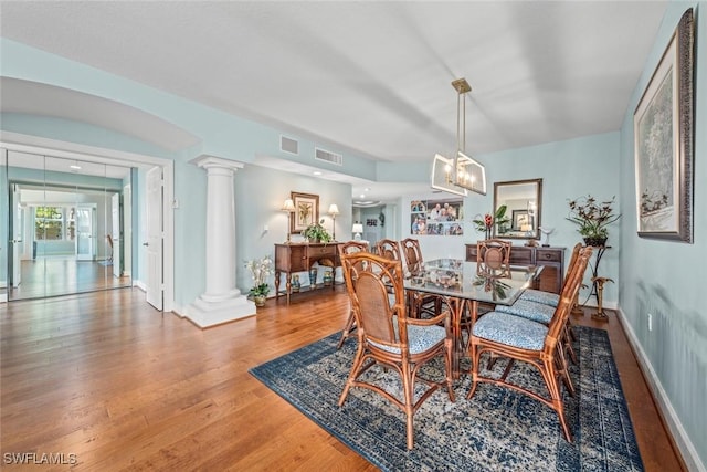 dining space featuring visible vents, ornate columns, and wood finished floors