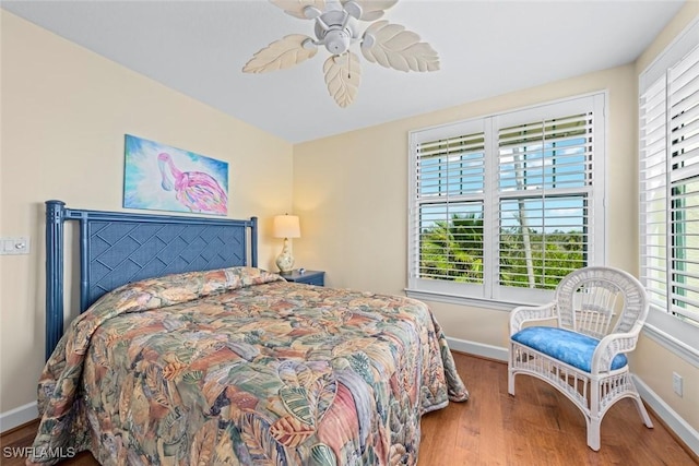 bedroom featuring baseboards, wood finished floors, and a ceiling fan